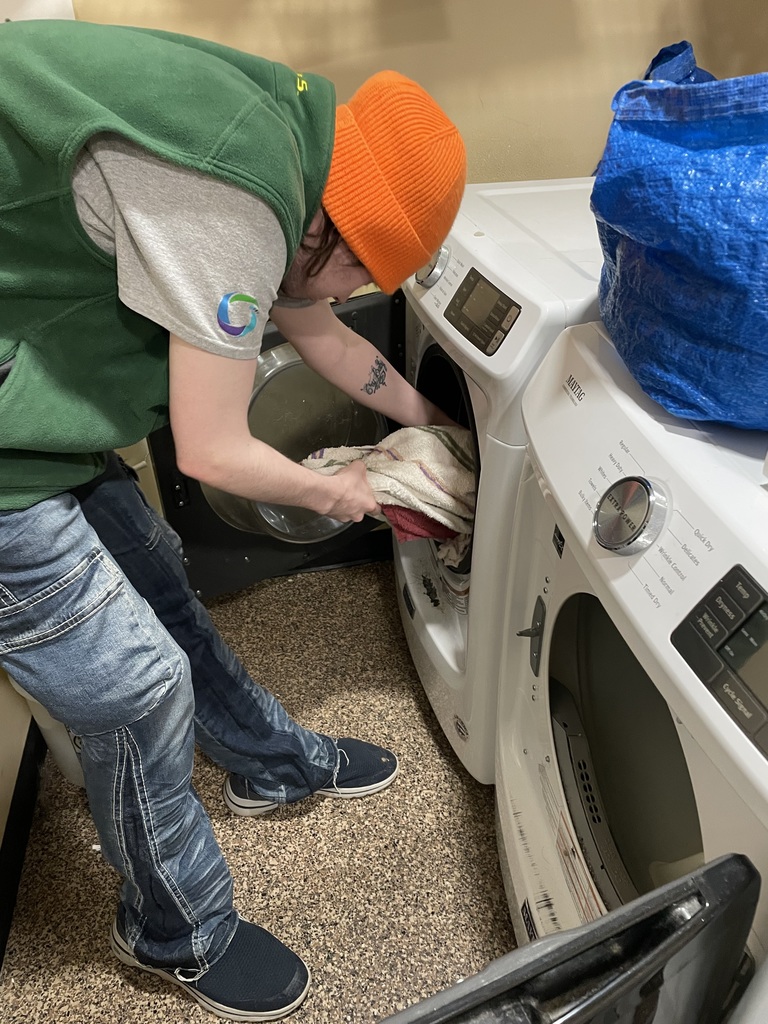 Person putting towels from the washer to the dryer