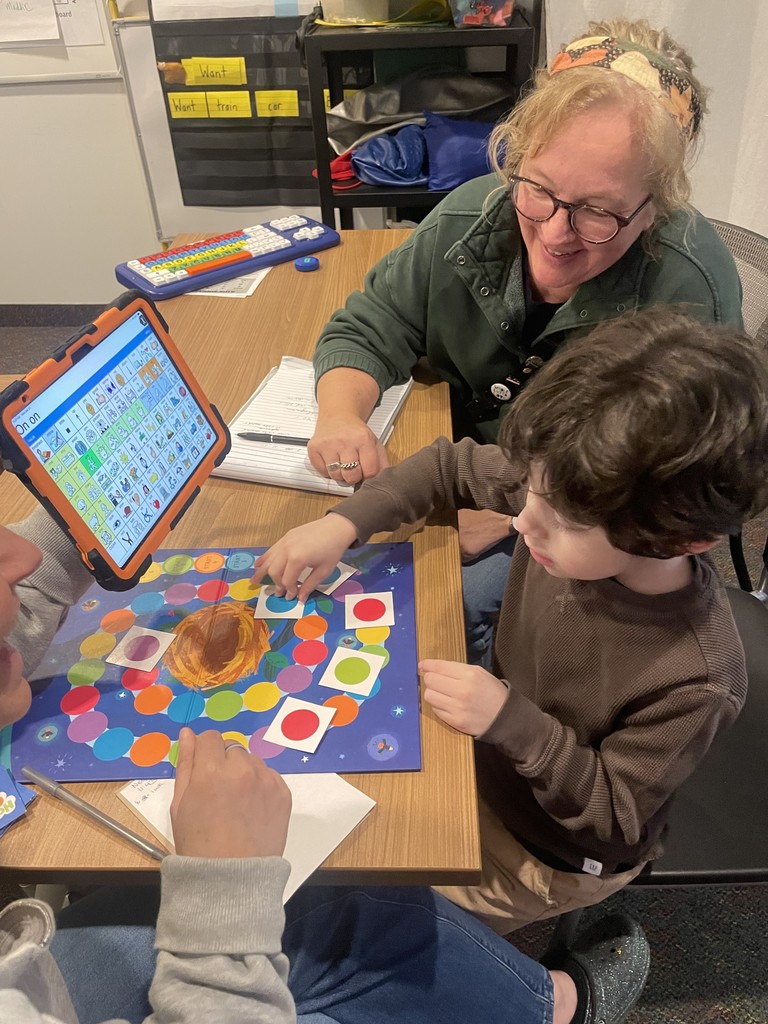 Student playing with a board game , sitting with an adult.
