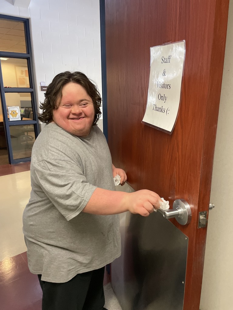 Student wiping a door handle.