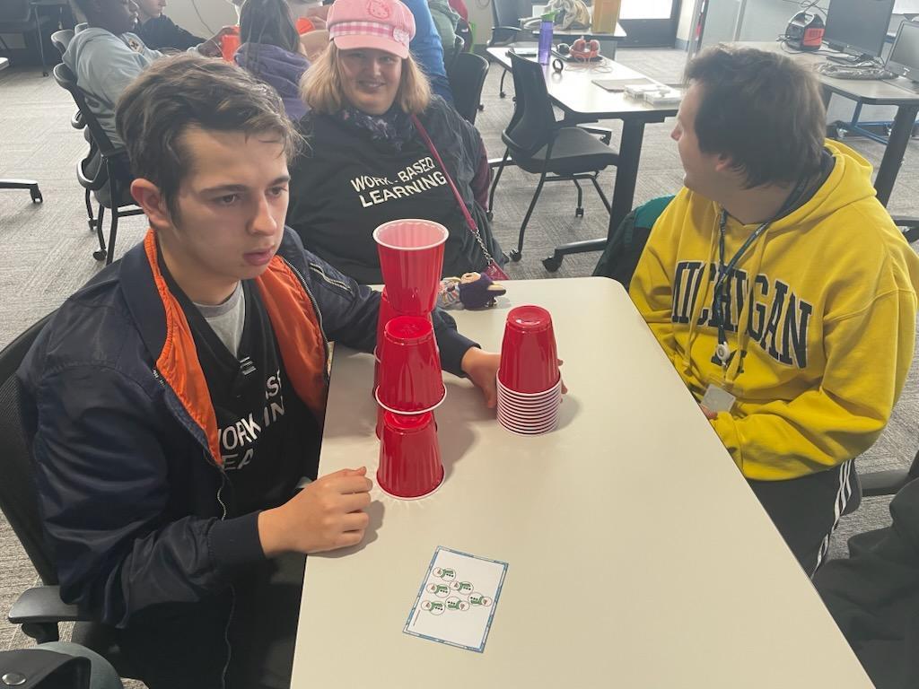 people sitting at a table stacking cups