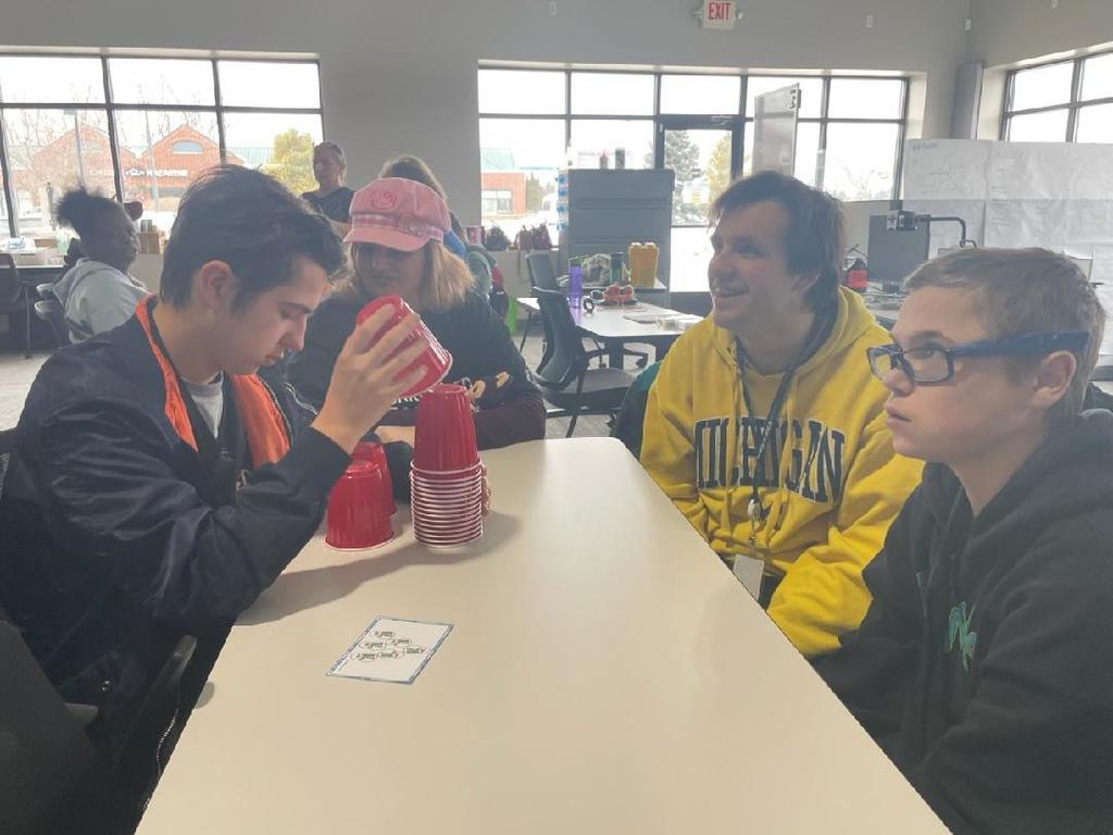 a group sitting around a table stacking stacking cups