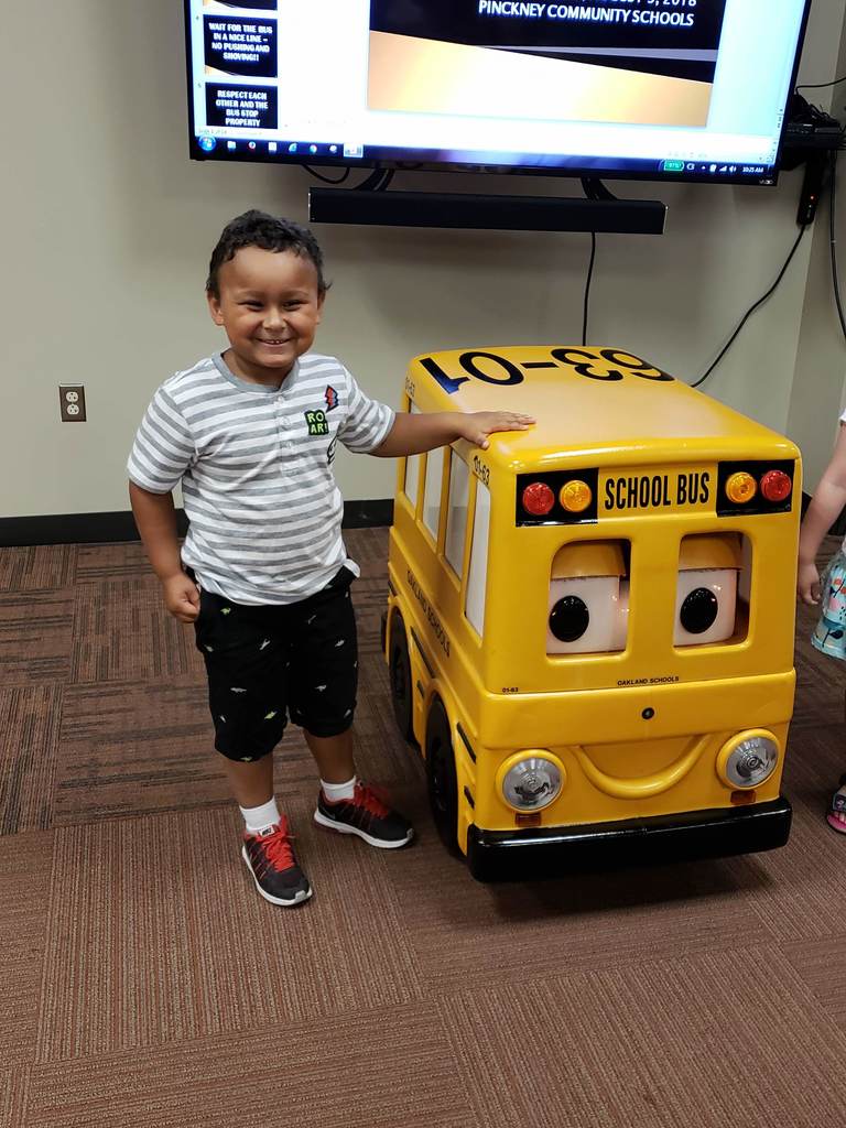 Photo of a small boy standing next to a robotic school bus