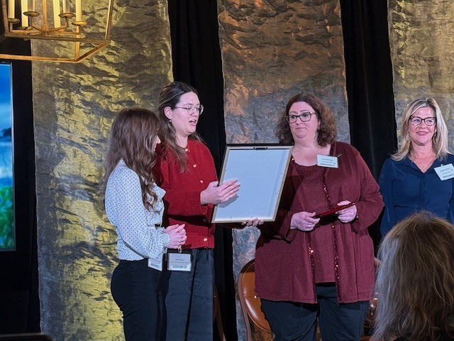 A woman presenting an award to another woman on a stage.