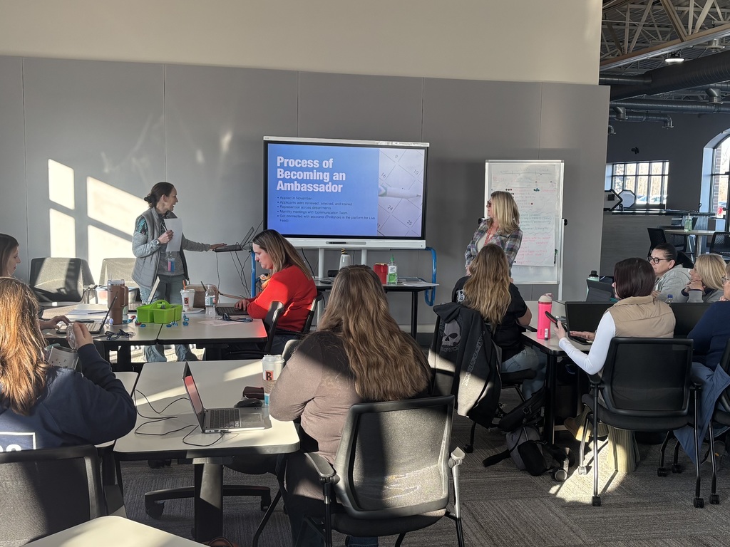 Two women presenting, using a whiteboard, to an audience in a classroom setting.