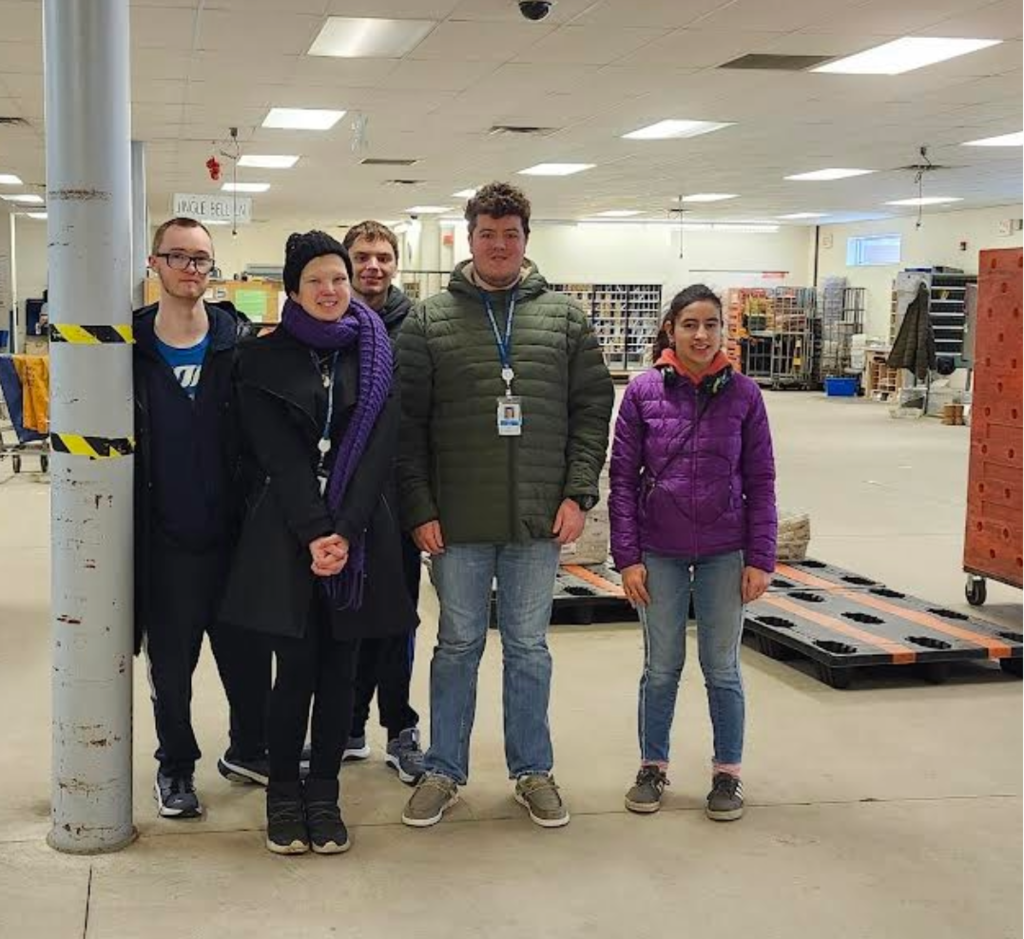 Group of learners standing in the sorting area of a post office.
