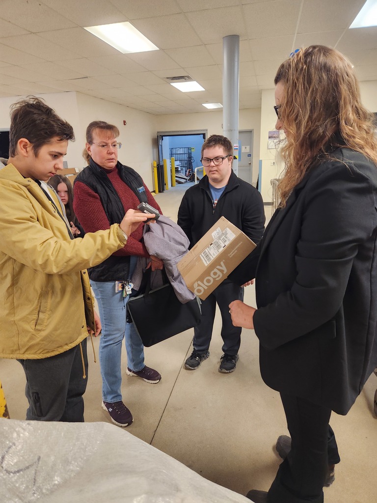 A teacher and young adult learners learning about the post office from the Post Master.