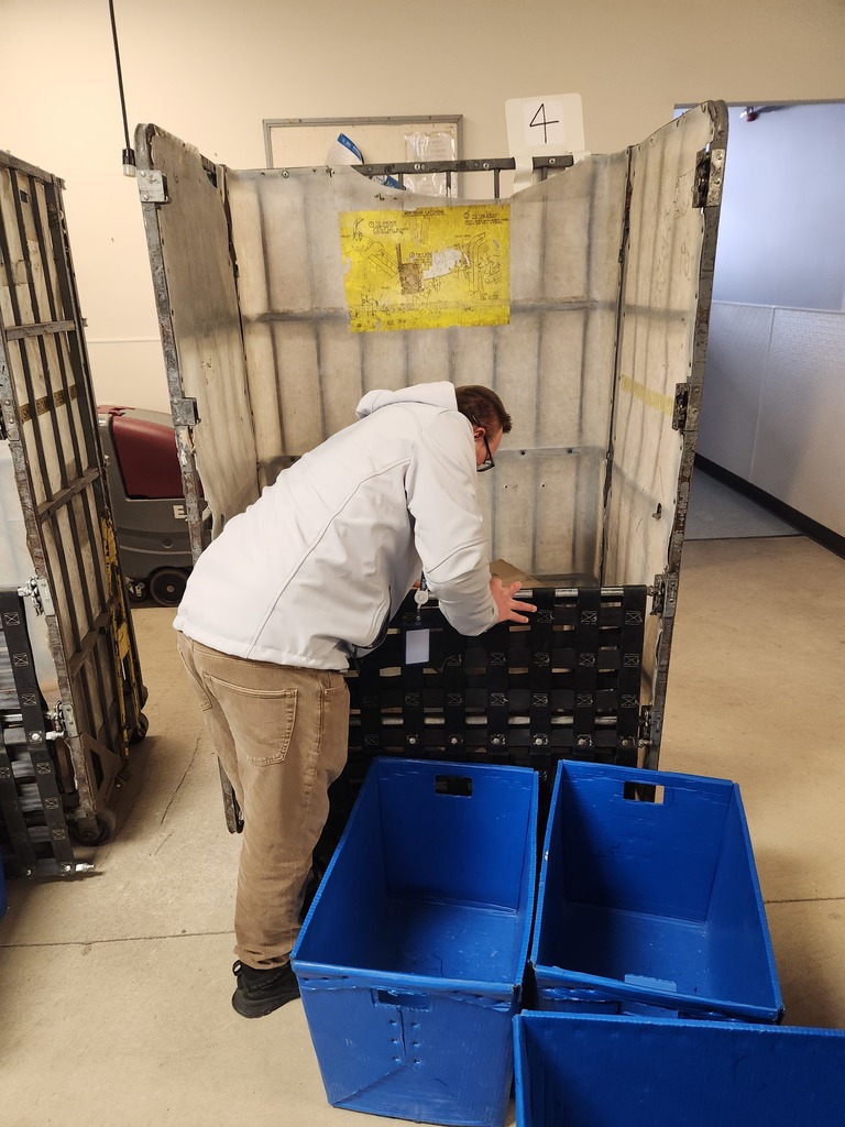 Young adult putting packages into a bin at the post office.