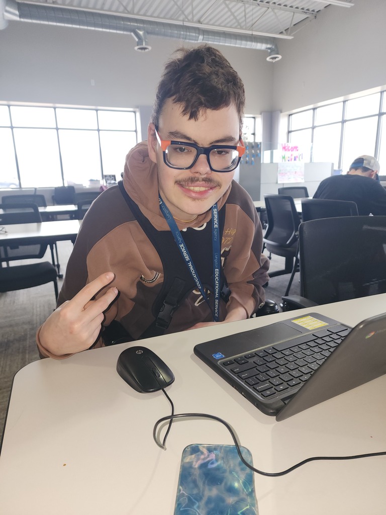 Young adult male sitting at a table with his laptop.