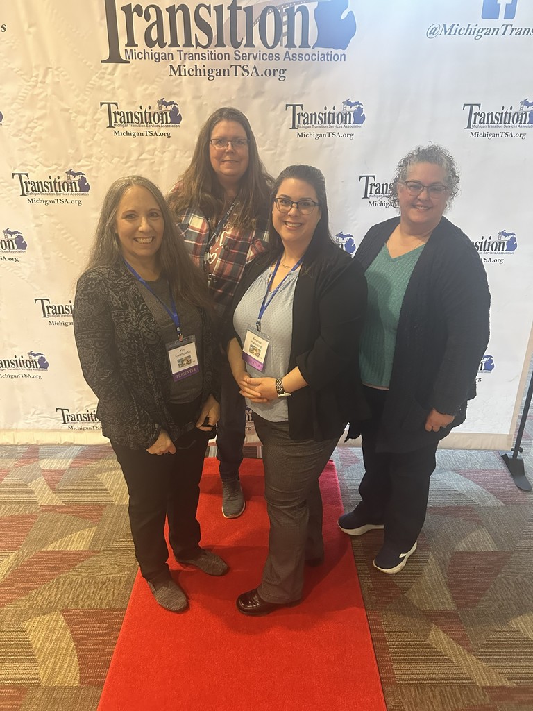 Group of ladies looking at the camera with Michigan Transition Services Photo back drop 