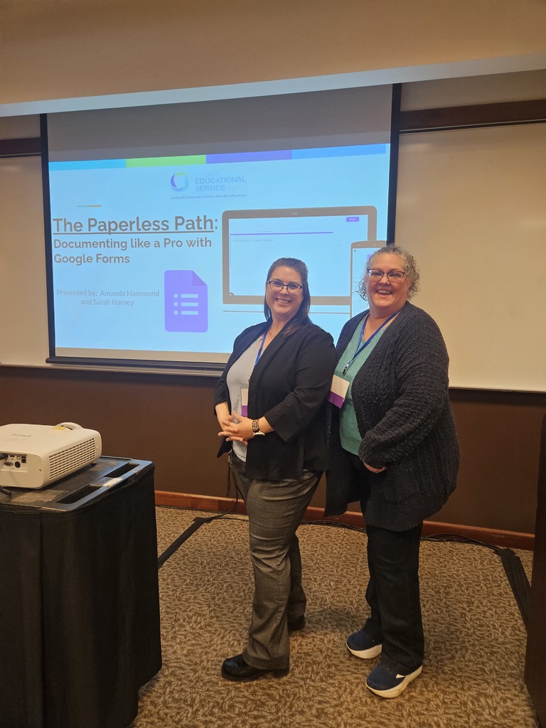 Two ladies standing new a screen that says the paperless path