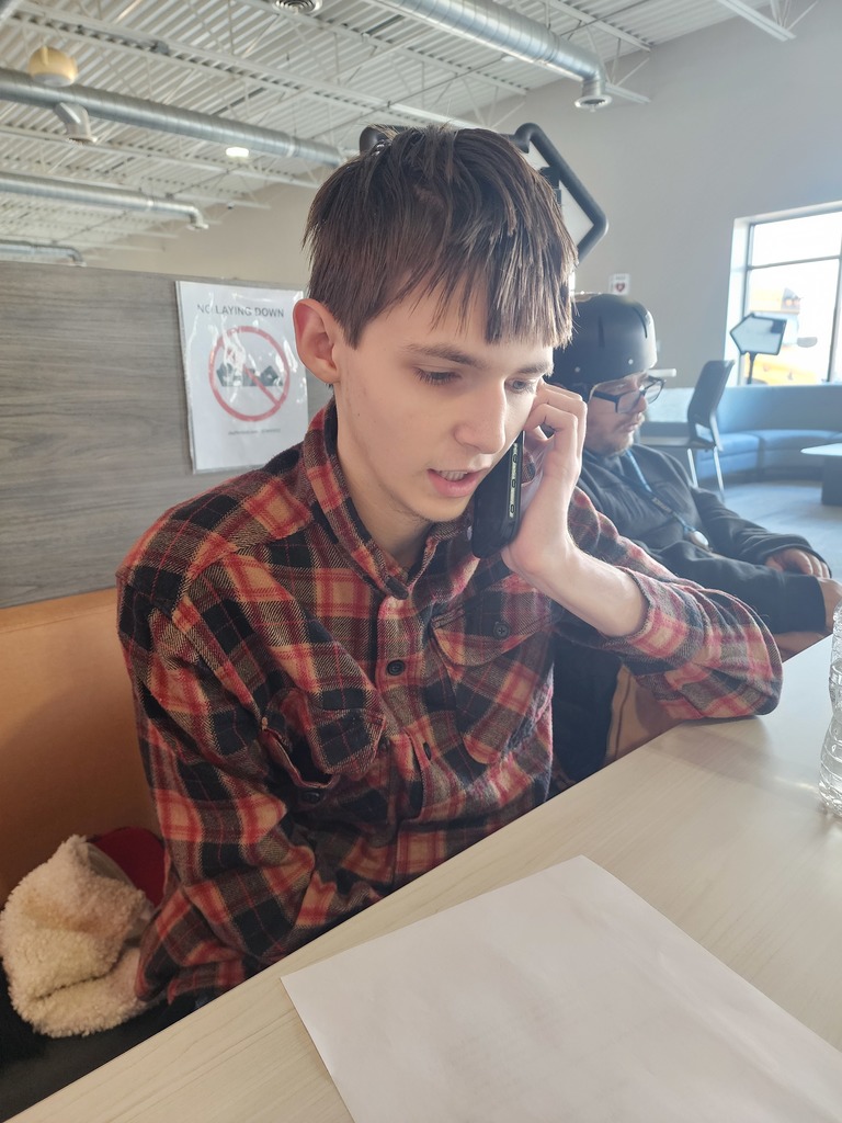 Young adult male making a phone call while sitting at a booth.