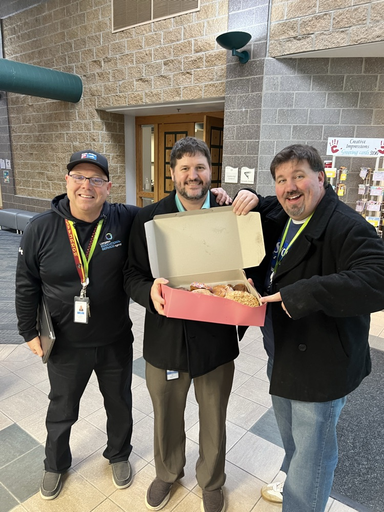 Three men with box of donuts 