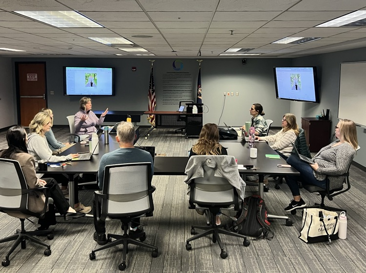 Conference room with many people sitting around a large table 