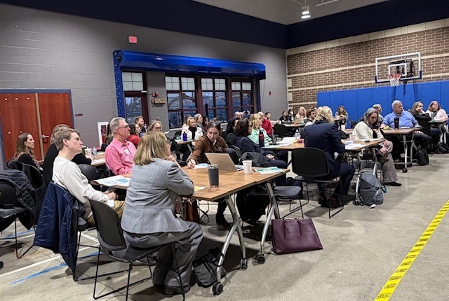 Group of  adults sitting in a conference room.
