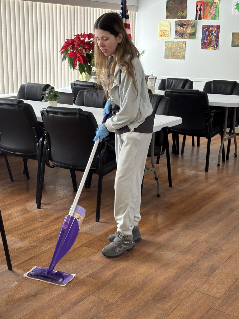 A young adult female mopping the floor.