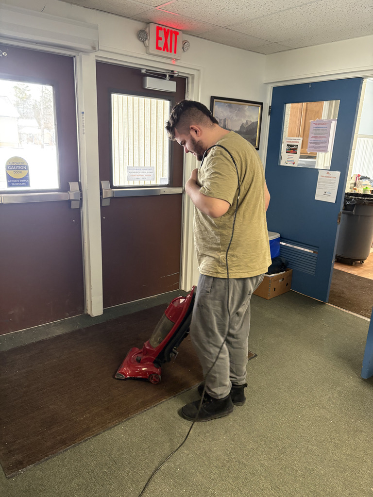 A young adult male vacuuming the floor.