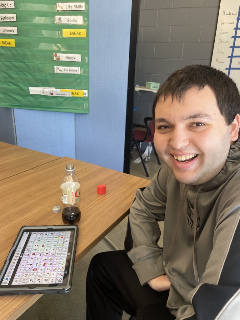 Student sitting at the table with a huge smile on his face.