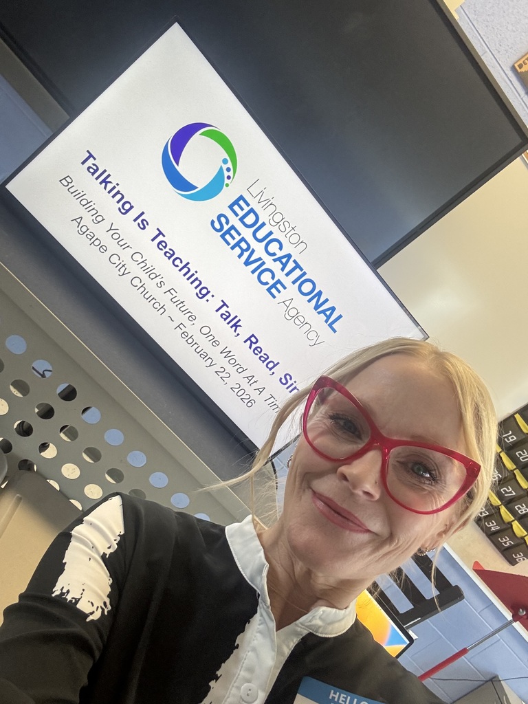 woman smiling, standing in front of a tv. 