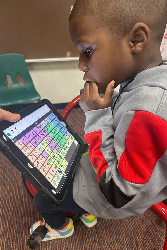Student sitting on a bike and looking at an AAC device.