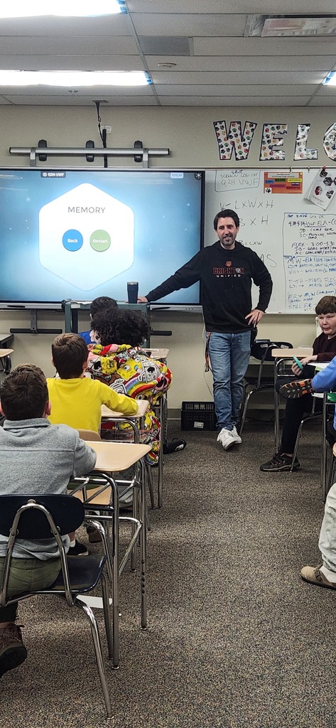 Children sitting at desks staring at teacher.