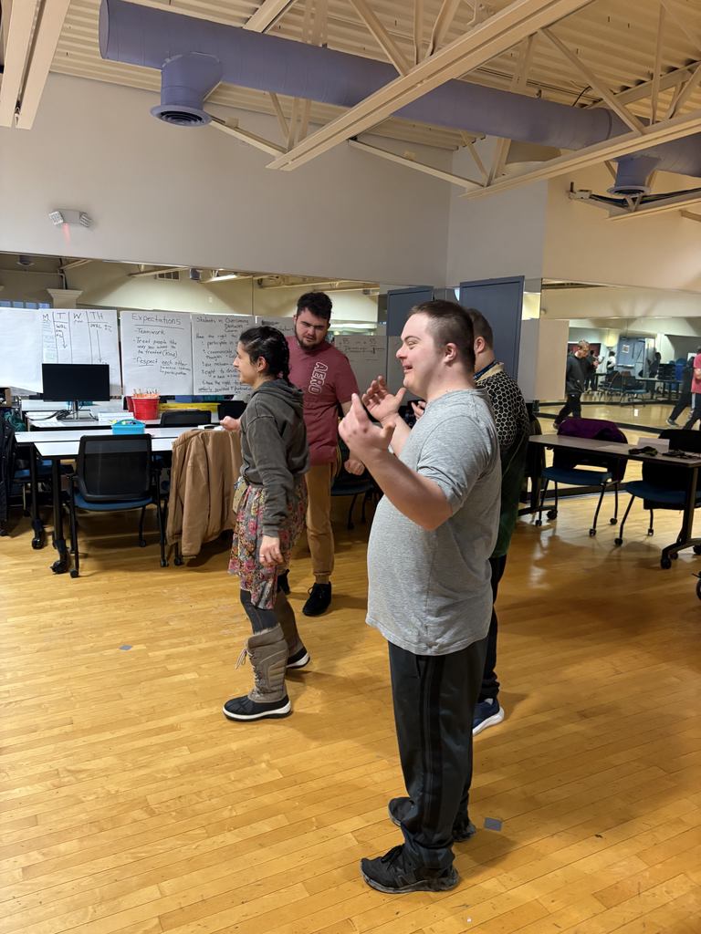 Four young adult students dancing.
