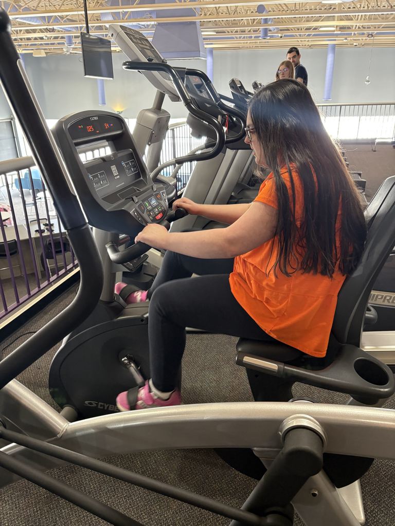 A young female adult riding a stationary bike.