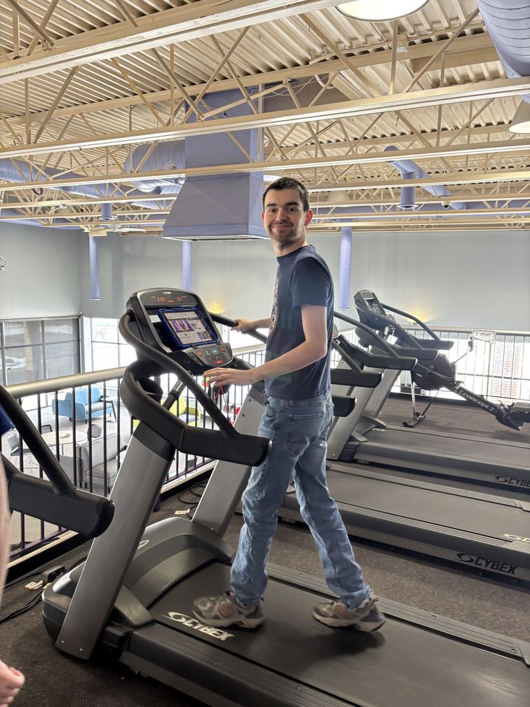 A young adult male walks on a treadmill.