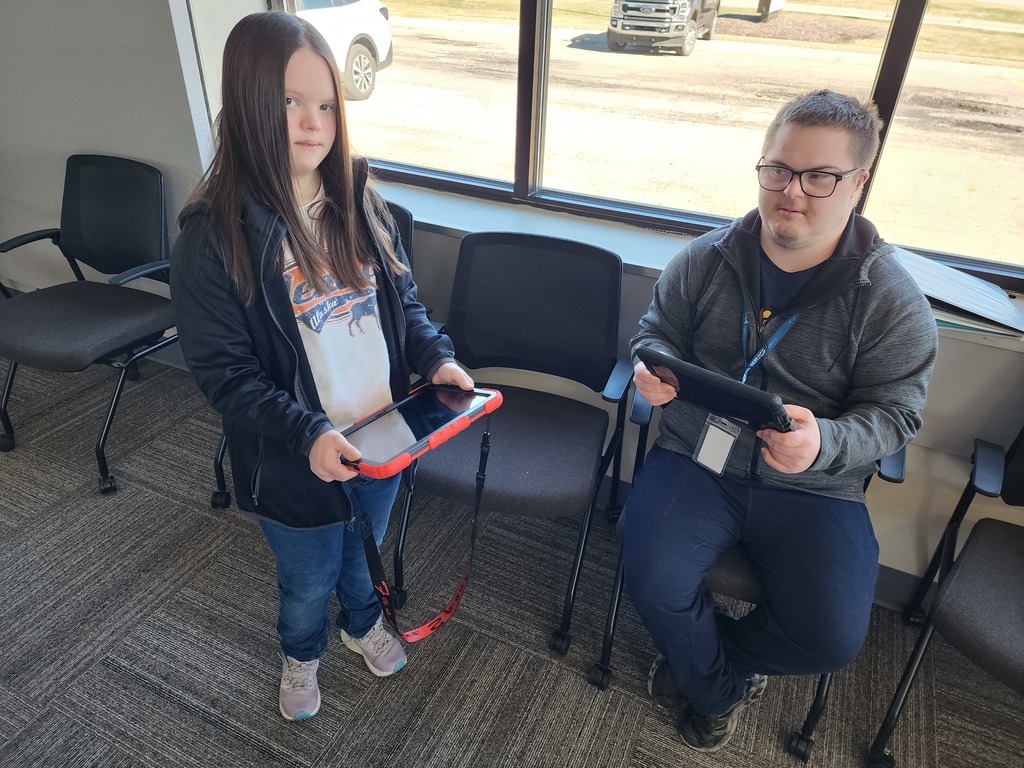 A young male and female are standing and holding their IPad's.