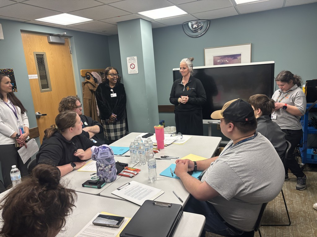 A group of people participating in a meeting or presentation in a small office room.