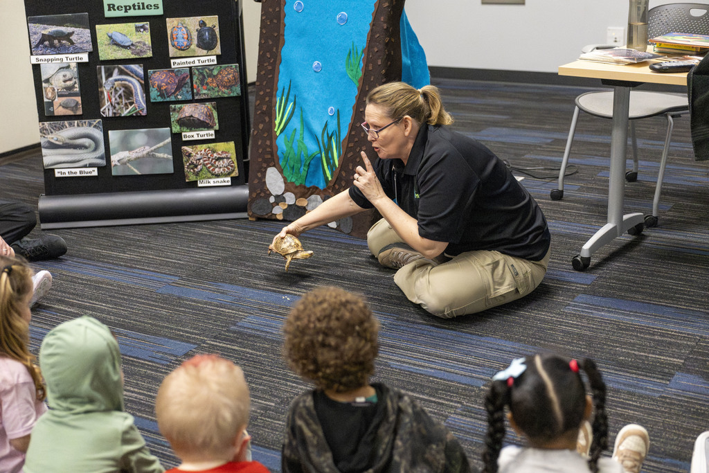 Woman showing a class of children a live turtle 