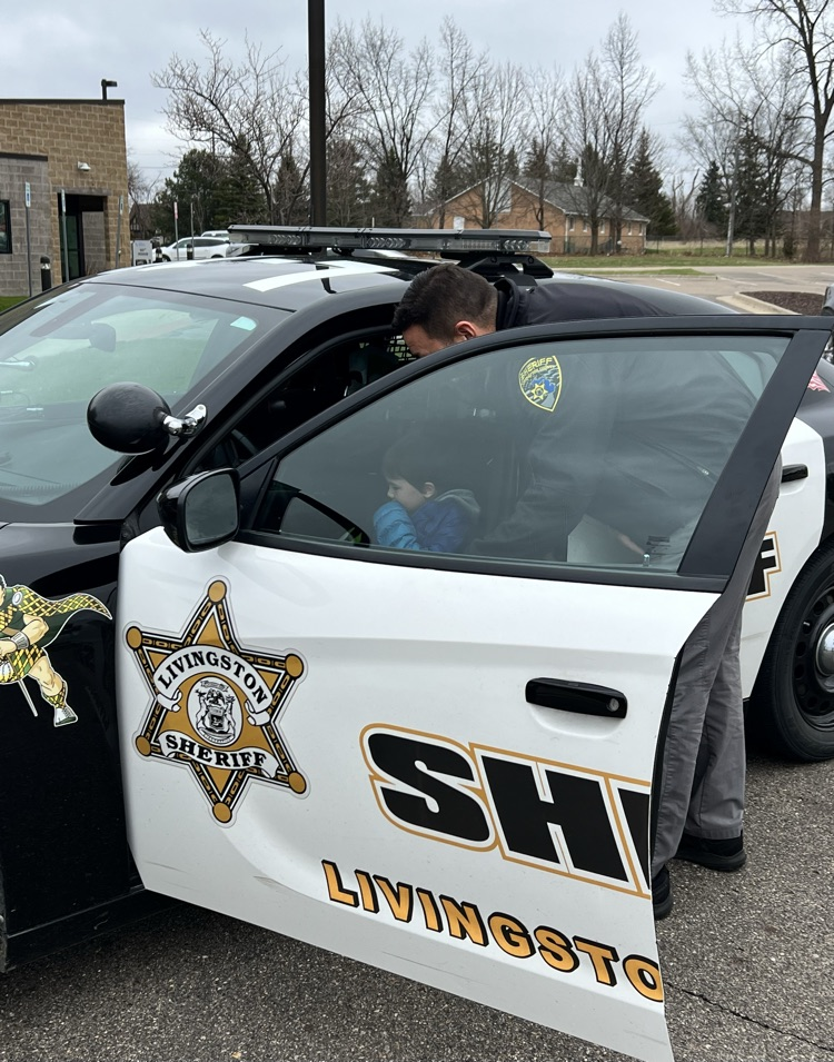 Sheriff showing young boy inside a patrol car 