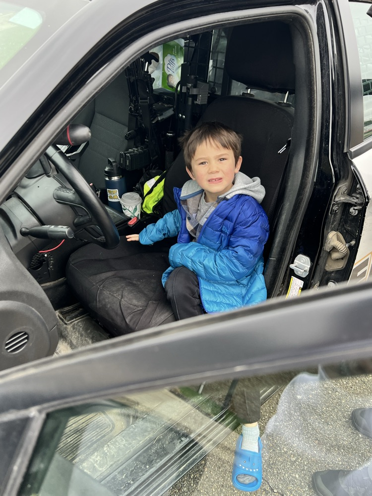 Young boy sitting in front seat of a patrol car 