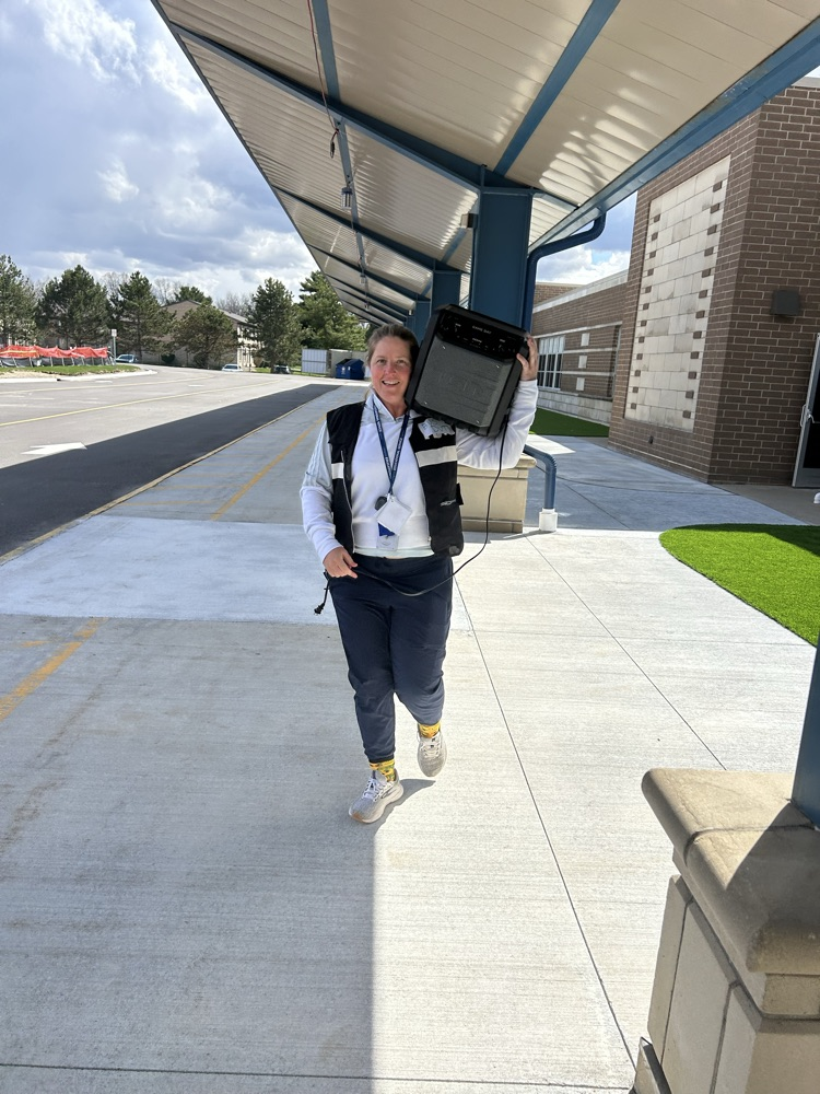 A woman is standing under an awning holding a boom box on her shoulder.