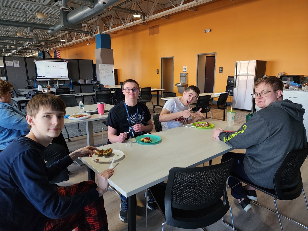 Four young adult males, sitting at a table while enjoying a meal.