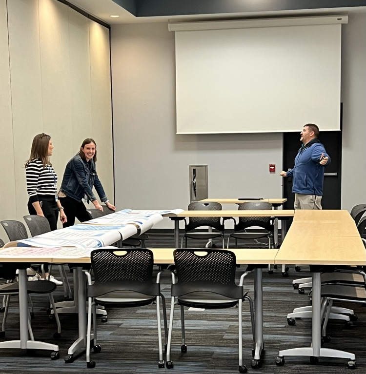 Two women and one man discuss content on a large screen 