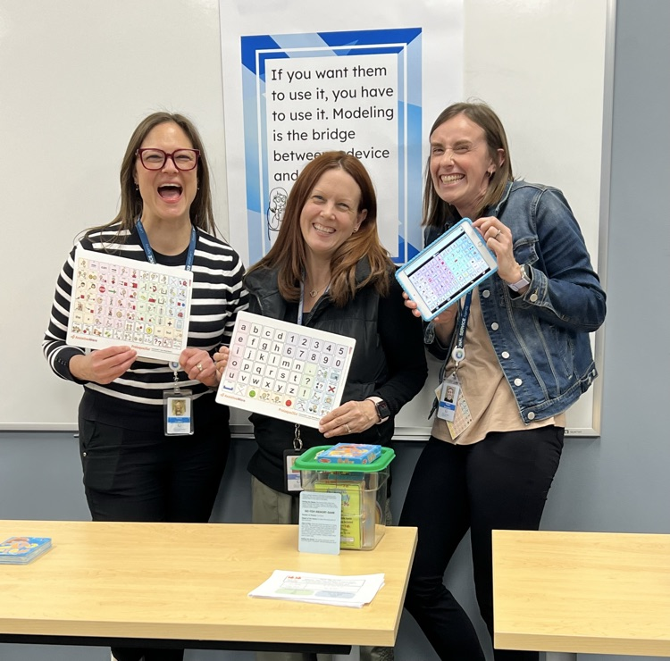 Three women pose for a photograph, each is holding a game. 
