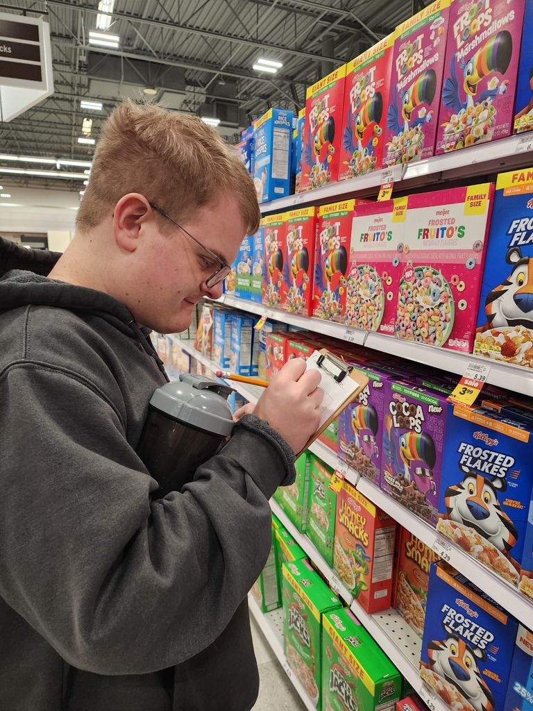 A young adult male looking at prices of cereal.