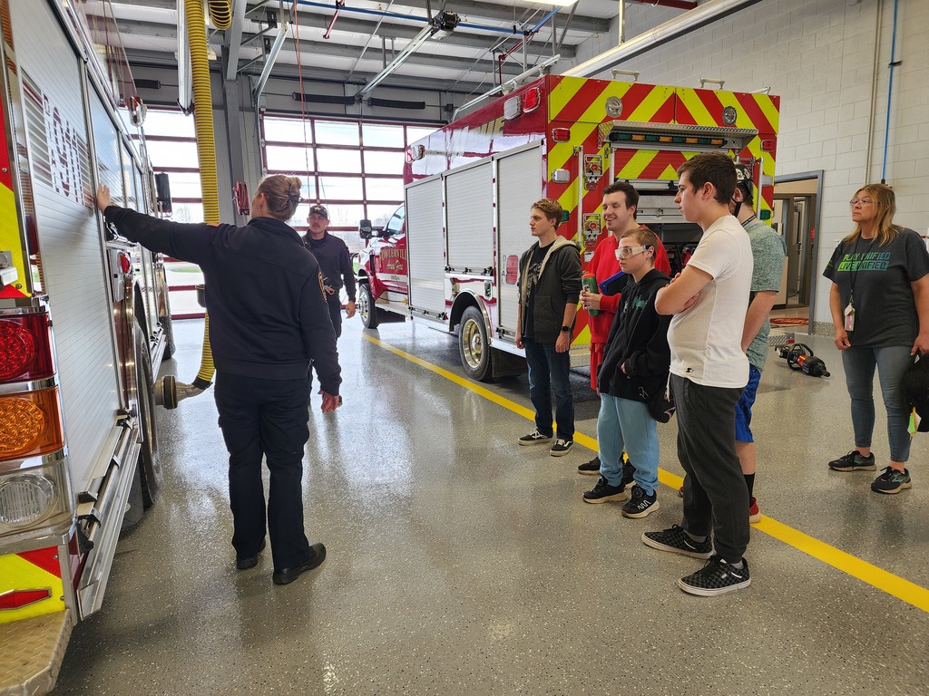 A group of young adults learning about the equipment on a fire truck.