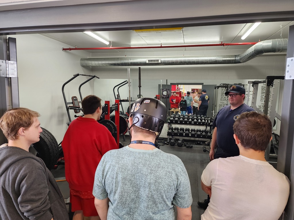 Young male adult learners and a fire person standing in a training room.