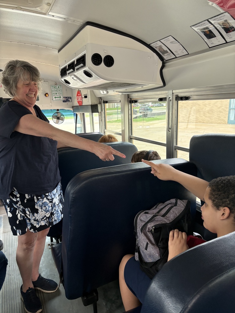 Woman pointing at student on the bus and student pointing back at her.