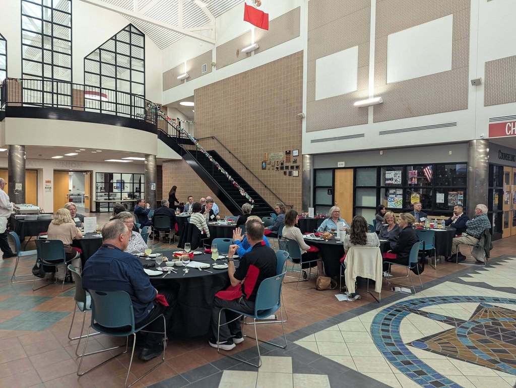 Large room filled with people seated at individual tables. 