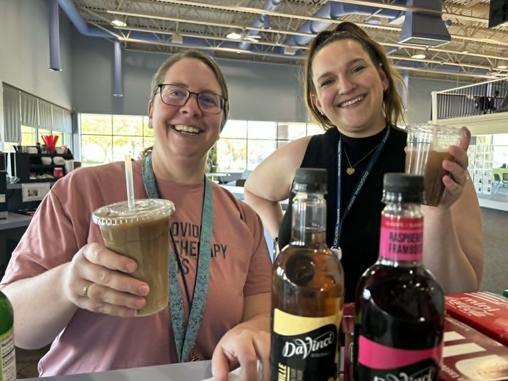 Speech therapist and school social worker smiling while holding cups of dirty soda