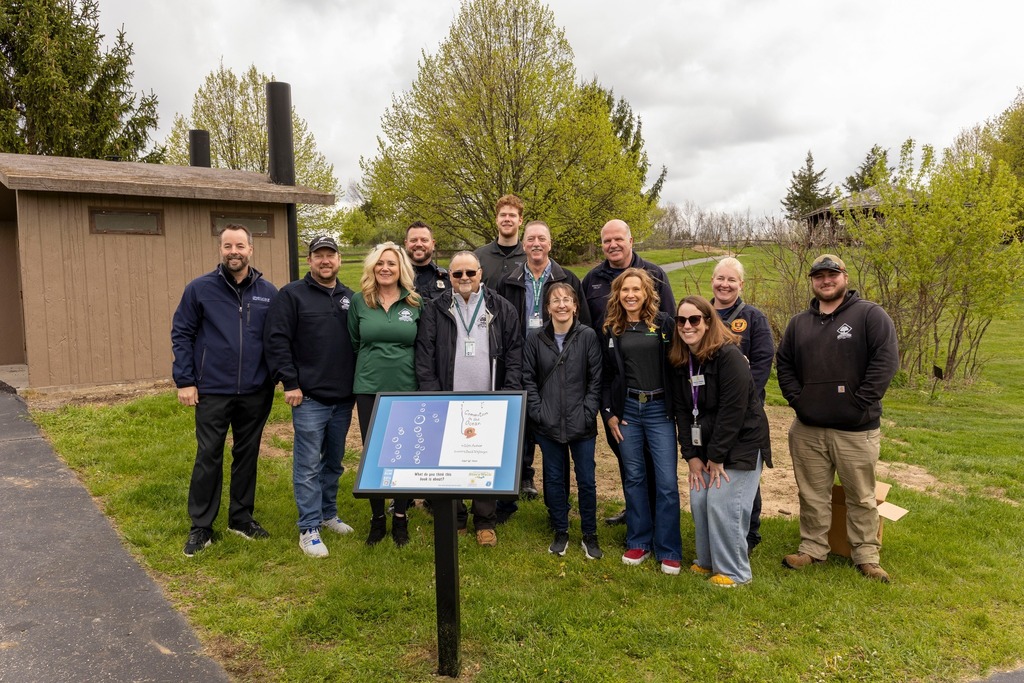 Group of people stand behind a sign.