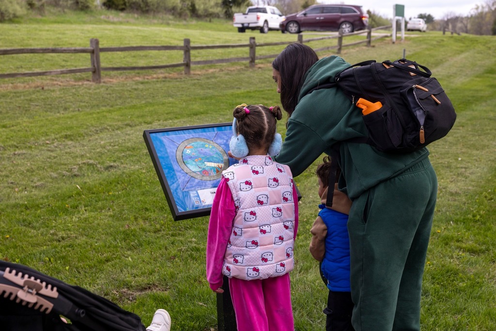 Mother and her two children reading a page from the story walk. 