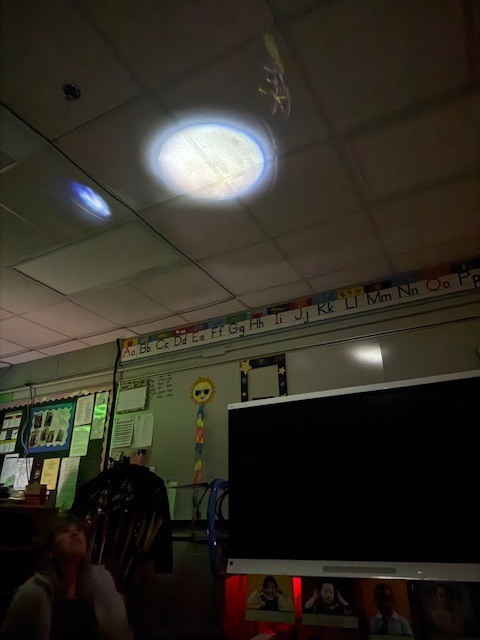 The moon image is projected onto the classroom ceiling while children watch and discuss what they notice.