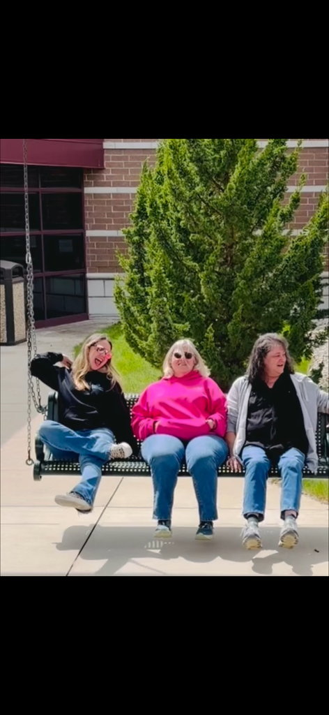 Three woman sitting on an outdoor swing, enjoying the sunshine.