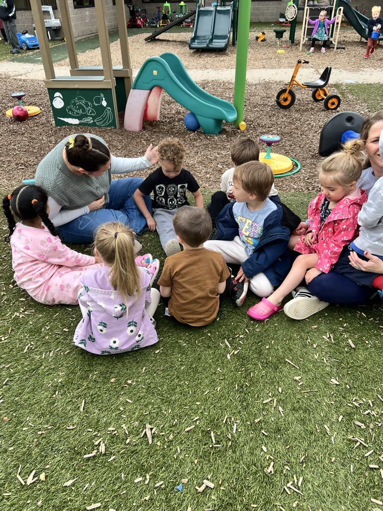 Young woman sitting in a circle on the ground with small children