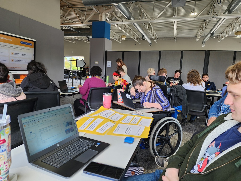 Classroom setting with learners working at tables and one in a wheel chair.