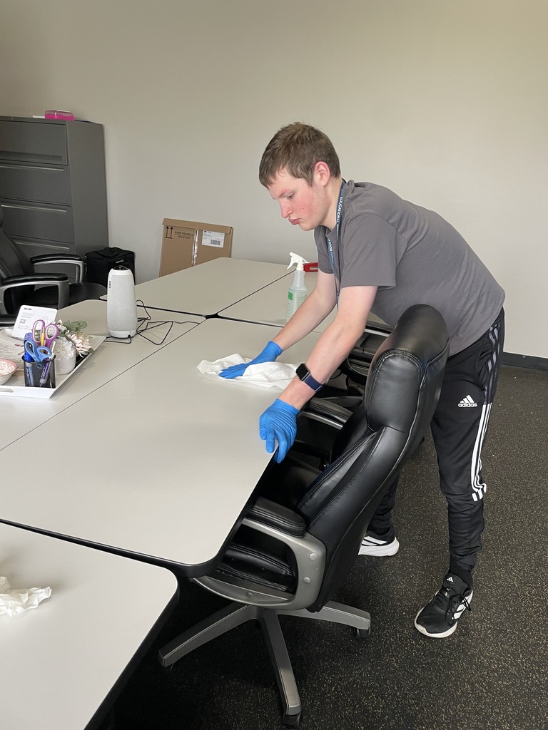 Student independently wiping down a table and practicing daily living and workplace readiness skills.