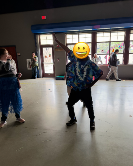 A student in a hawaiian shirt and lei showing his dance moves